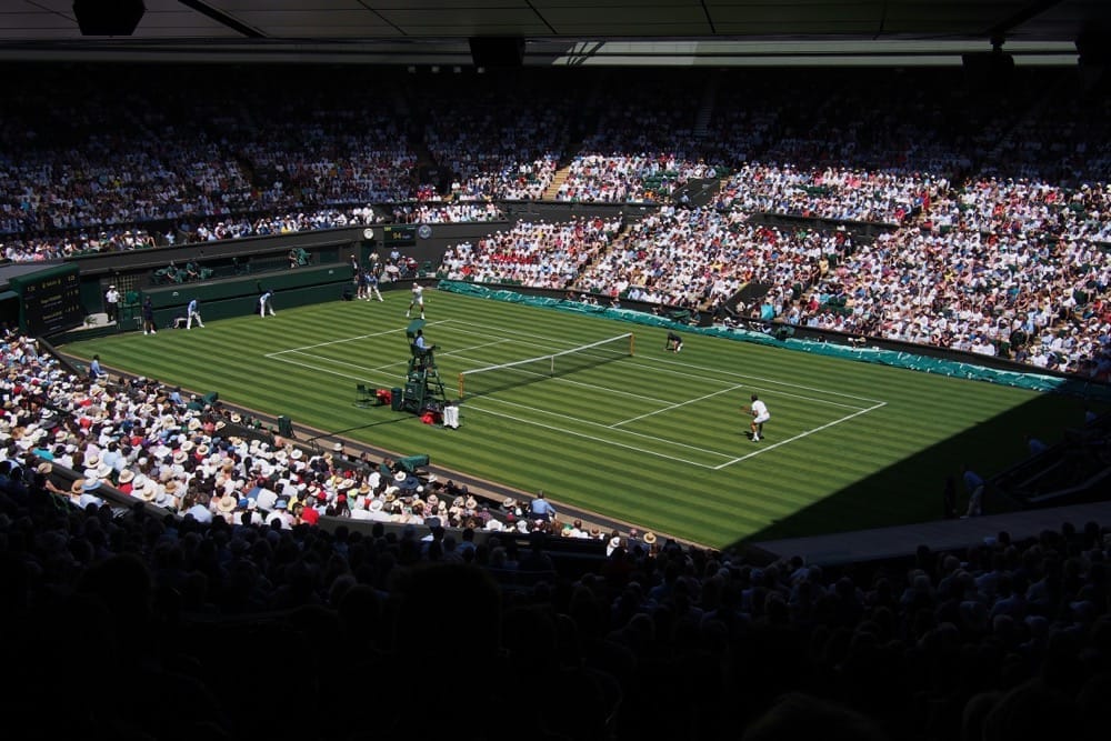 Packed crowd watching a match on Wimbledon's Centre Court grass tennis court