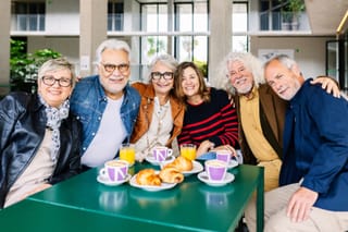 Image of a group of six seniors having a social event with coffee and croissants