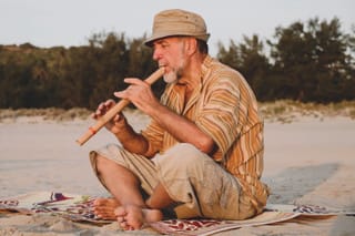 Picture of a senior man on the beach playing a recorder