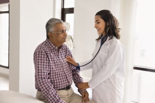 Image of a senior man with coronary heart disease being checked by a doctor with a stethescope