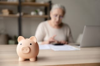 Picture of a piggy bank with a senior woman in the background 