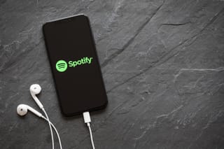 Picture of a smart phone with the Spotify app and earbuds