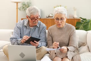 Photo of couple sitting on couch working on tax planning together