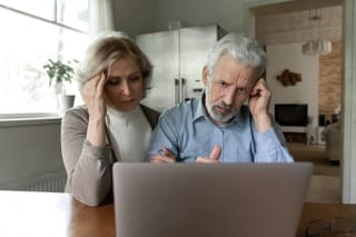 Picture of a senior couple with a puzzled look looking at their laptop computer