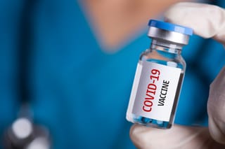 Photo of a vial with a label stating "COVID-19 vaccine"