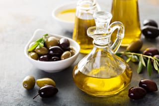 Picture of olive oil in a vintage bottle along with green and black olives