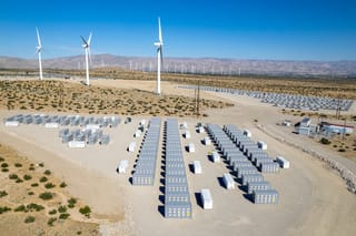 Picture of a desert power plant with windmills and battery storage