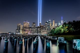 Picture of the 9/11 Memorial from a distance at night showing the lights representing the World Trade Center towers 