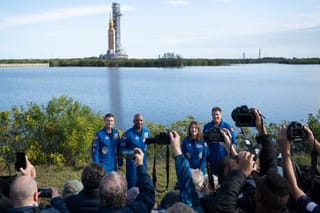Picture of the Artemis II crew with Artemis II on the launchpad in the background