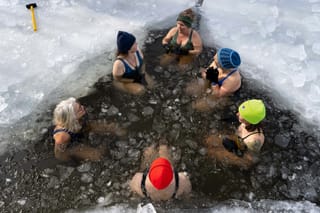 Picture of a group of people doing a cold plunge in frozen water 