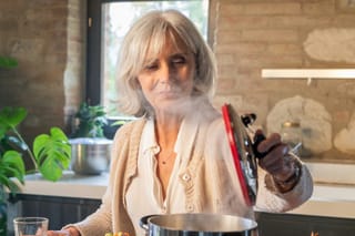 Image of older woman lifting the the of a pot