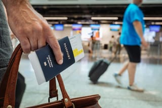 Image of a person walking in an airport holding a bag and a passport