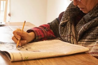 Image of an older woman working on a crossword puzzle.