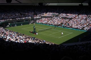 Packed crowd watching a match on Wimbledon's Centre Court grass tennis court