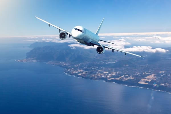 Picture of a commercial airliner taking of from an island with mountains