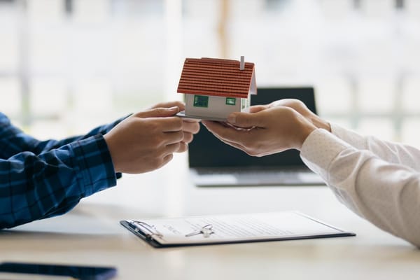 Photo of a model house being transferred between people