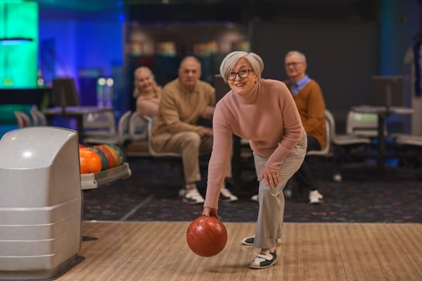 Image of a senior woman bowling with friends watching