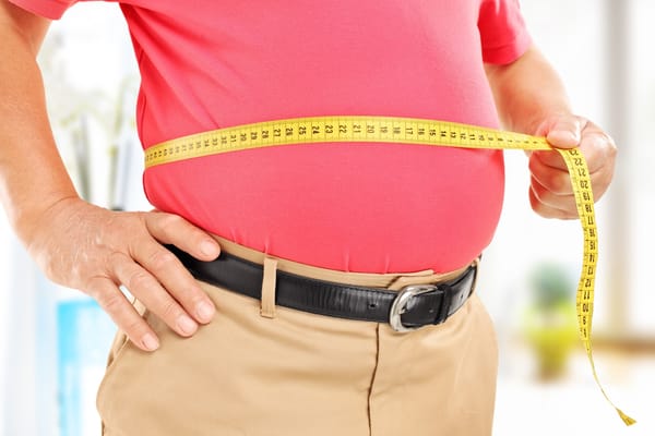 Image of a senior man measuring belly fat with a tape measure