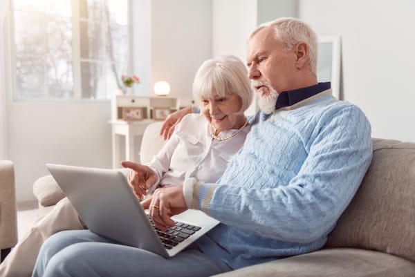 Image of an older couple reading off a laptop