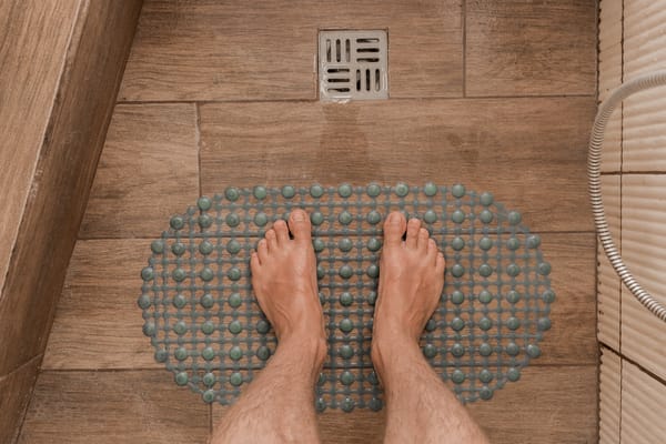 Picture of a person's feet standing on a non-slip mat in a shower