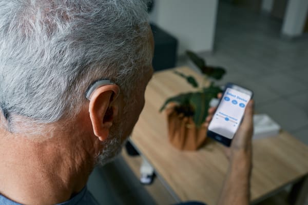 Senior man with a hearing aid controlled by a smart phone with an app