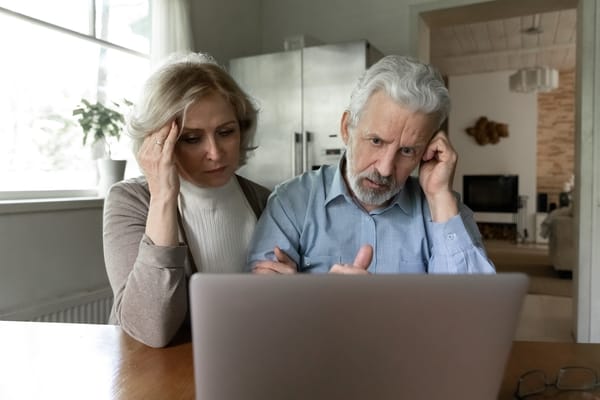 Picture of a senior couple with a puzzled look looking at their laptop computer