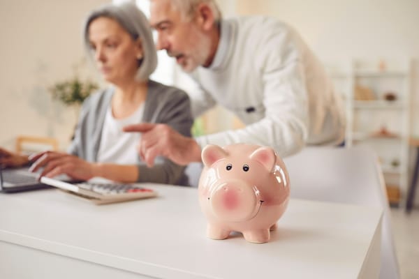 Picture of a piggy bank and senior couple evaluating their savings to determine the safe withdrawal rate 