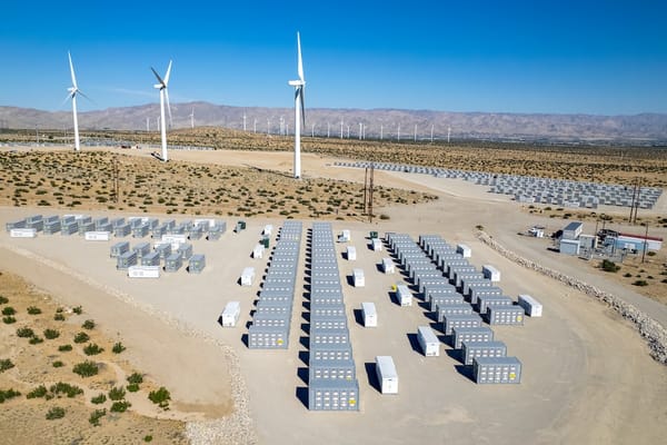 Picture of a desert power plant with windmills and battery storage
