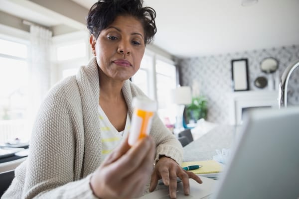 Picture of a woman reading the label on a prescription bottle