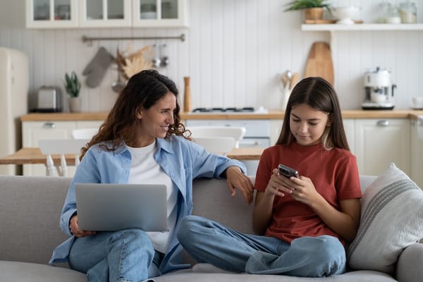 Picture of a mother holding a computer and her child holding a smartphone