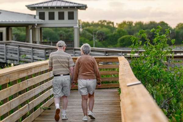 Photo of a senior couple walking on a boardwalk 