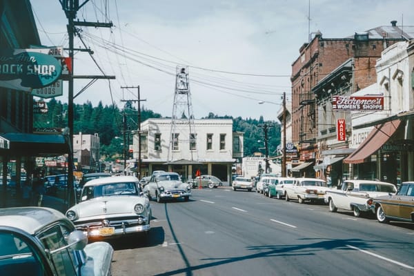 Image of a street with parked cars and buildings